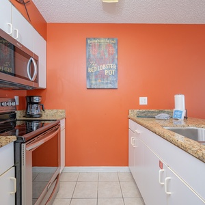 This kitchen features stainless appliances, vibrant red walls, and granite countertops, perfect for culinary adventures