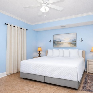 Guest bedroom featuring a king-size bed, soft blue walls, and coastal-themed decor for a relaxing retreat