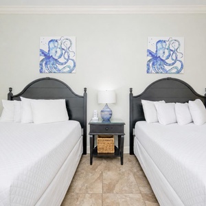 Relaxing guest bedroom featuring two comfortable queen beds and charming artwork on the walls
