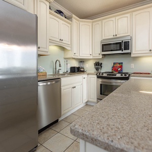 Bright cabinetry complements the granite countertops in this kitchen, featuring a convenient breakfast bar and coffee station