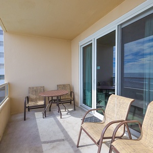 This balcony features comfortable seating and a table, perfect for enjoying a beachfront view