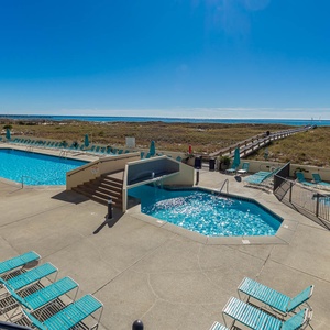 Inviting pool area features a large swimming pool and a kiddie pool, with lounge chairs and a scenic view of the beach beyond