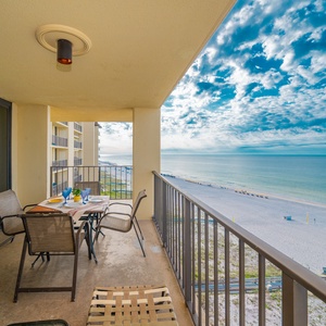 Balcony featuring a dining table with chairs, offering a serene view of the beach and gentle waves beyond