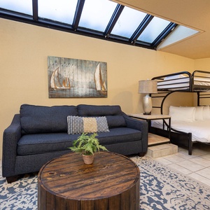 This cozy patio area features a dark blue sofa, a wooden coffee table, and a unique twin over double bunk bed setup