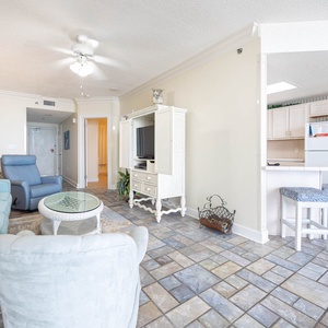 Cozy living area features a light blue sofa, plush chairs, stylish tile flooring, creating a relaxing vibe