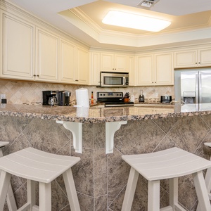 Kitchen with granite countertops, stainless appliances, coffee station, and cozy bar seating for a casual dining experience
