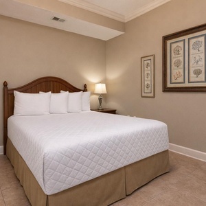 Guest featuring a plush queen bed, decorative coral artwork, and soft lighting for a relaxing atmosphere