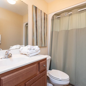This bathroom features a clean design with a light-colored vanity, fresh towels, and a soothing green shower curtain