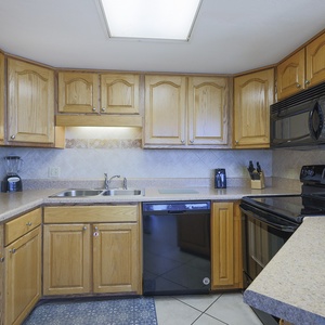 The kitchen features wooden cabinetry, a black refrigerator, and a sleek countertop with essential appliances for meal prep