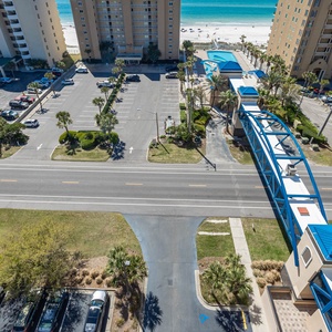 This view showcases a vibrant beachside community with palm trees lining the parking area, leading to stunning beach access