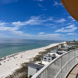 Relax on the balcony with salt-kissed air as umbrellas and swimmers dot the beach below