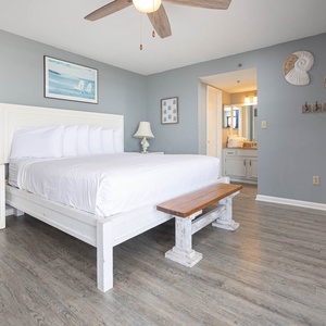 The master bedroom features a comfortable king bed, charming coastal decor, and a cozy seating area, perfect for relaxation