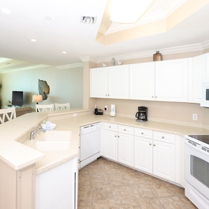 Prepare meals in this kitchen with sleek cabinetry, white appliances, and spacious countertops