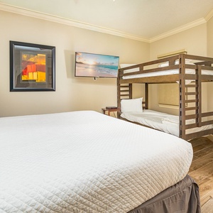 Relax in this cozy guest bedroom featuring a plushking  bed, tiwn bunk beds for extra guests, and a flat-screen TV