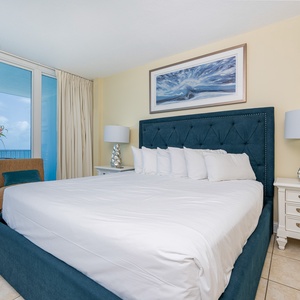 The master bedroom features a plush bed, stylish decor, and a stunning beachfront view with balcony access