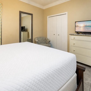 Guest bedroom features a plush king bed, a TV on a dresser, and a patterned accent wall, creating a welcoming retreat