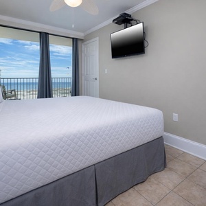 This bedroom features a comfortable bed, a flat-screen TV, and stunning beachfront views through large windows