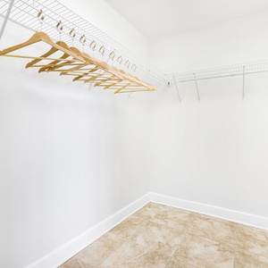 This spacious master closet features organized shelving and wooden hangers for convenient storage of your belongings