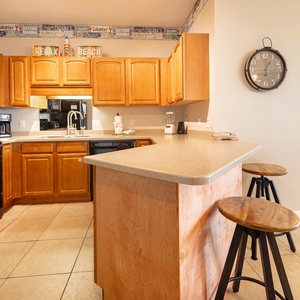 Prepare meals in this stylish kitchen, featuring black appliances and warm wooden cabinetry