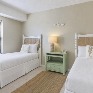 Charming guest room with two twin beds, a light green nightstand, and coastal decor