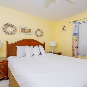 This bright bedroom features a comfortable bed with fluffy pillows, cheerful yellow walls, and beach-themed décor