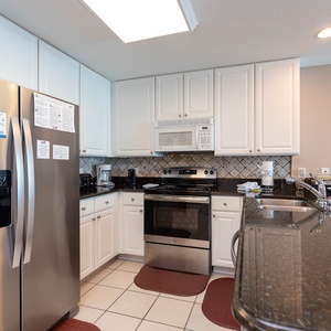 This modern kitchen features stainless appliances, granite countertops, and a cozy dining area with a view of the beach