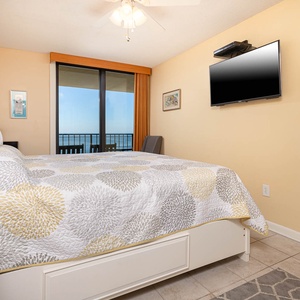 Cozy master bedroom featuring a king bed, wall-mounted TV, and a beautiful view through sliding glass doors
