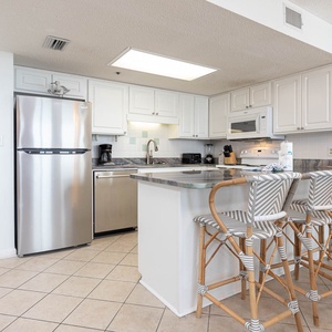 White cabinetry and a sleek breakfast bar complement the modern kitchen, featuring stylish bar stools for casual dining