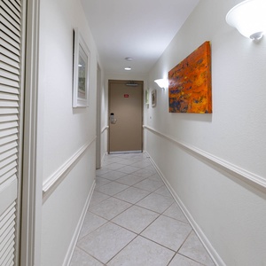 Step into a welcoming hallway adorned with artwork, leading you to your beachfront vacation retreat
