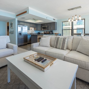 Inviting living area featuring plush sofas, a stylish coffee table, and a modern kitchen in the background