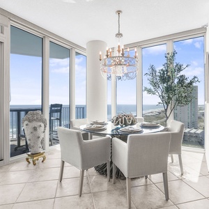 This dining area features a stunning view, a stylish chandelier, and a glass table set for an elegant meal