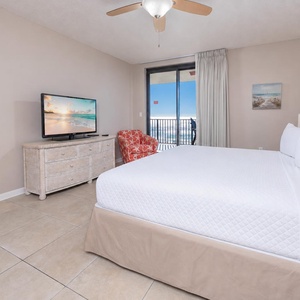 Cozy master suite featuring a large king bed, vibrant chair, and a view that invites the beach into your room