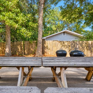 Gather around the picnic table with a grill nearby, perfect for outdoor meals and relaxation under the trees