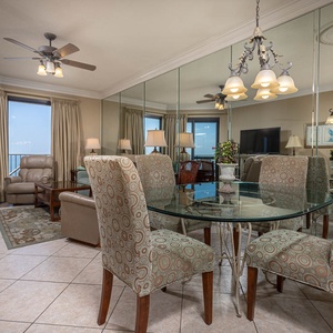 Dining area features a glass table with chairs, overlooking the balcony and the serene gulf view through large windows