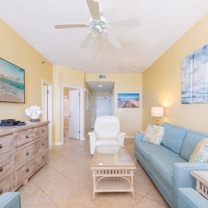 The inviting living area features teal sofas with a queen sleper, a rustic dresser, and a large TV, enhancing relaxation