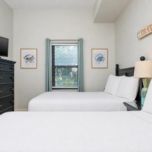 Relax in this guest bedroom featuring a queen and twin bed, TV, and charming decor for a restful night's sleep