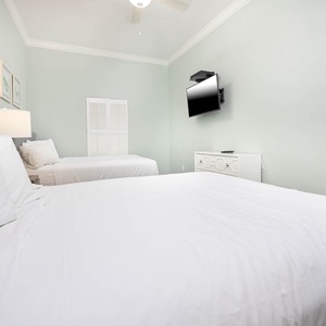 Relax in this guest bedroom featuring two queen beds and a wall-mounted TV for entertainment