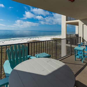 Balcony with turquoise seating offers a serene view of the beach and calm gulf waters, perfect for relaxation