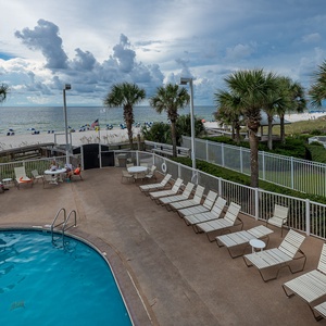 This inviting pool area features lounge chairs and a stunning beachfront view, perfect for relaxation and fun in the sun