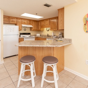 Bright wooden cabinetry complements the granite countertops in this inviting kitchen, featuring a breakfast bar with seating