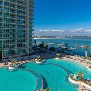 This stunning view showcases a sparkling pool surrounded by palm trees and a serene bay view, perfect for relaxation