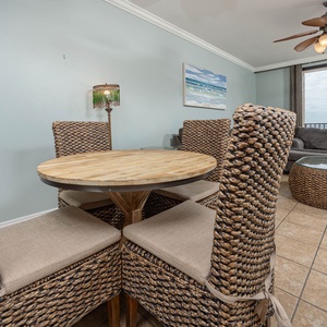 Gather around the round dining table with woven chairs, enjoying the inviting coastal decor and natural light