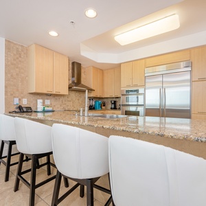 Modern kitchen featuring stainless appliances, granite countertops, Keurig and coffee maker, and stylish bar seating