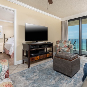 This living area features a large TV, colorful seating, and a breathtaking view from the balcony