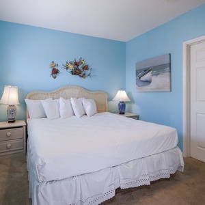 Cozy guest bedroom featuring a plush king bed, vibrant blue walls, and nautical decor, creating a serene retreat for guests
