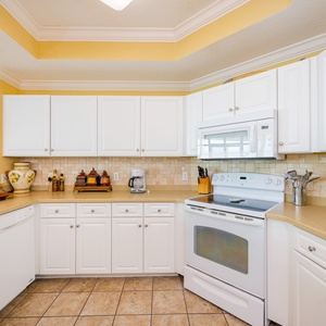 Prepare meals in this kitchen with sleek cabinetry, white appliances, and spacious countertops