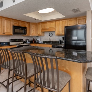 Enjoy the inviting atmosphere of this modern kitchen with sleek granite countertops and ample seating at the breakfast bar