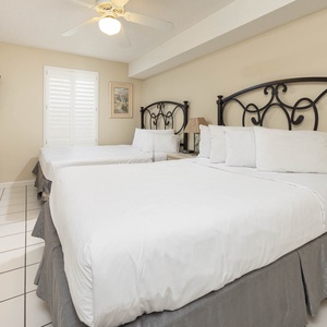 Guest room featuring two queen beds, a TV, and natural light from the window, creating a relaxed and inviting atmosphere