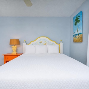 This bedroom features a bright yellow and white headboard, colorful decor, and a cozy atmosphere perfect for relaxation