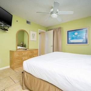 Brightly colored guest bedroom featuring a cozy king bed, wall-mounted TV, and charming decor for a relaxing getaway
